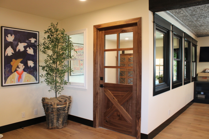 A row of matched black-framed windows running along an interior wall next to a walnut door
