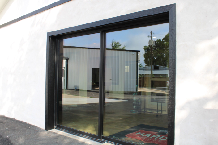Exterior view of a large black-framed slider window set into a white stucco wall