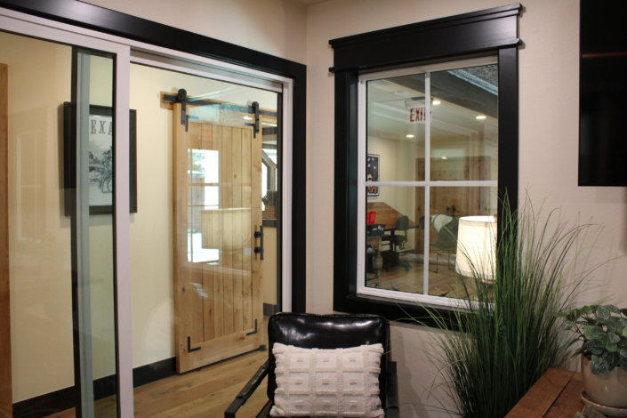 Black-framed window with grid pattern and matching black trim beside a wood barn door
