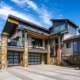 Modern luxury home with stone accents, expansive windows, covered balcony, and three-car garage